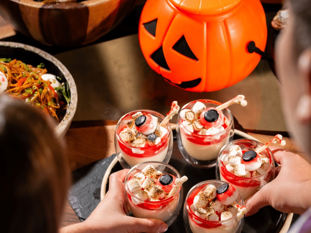 Halloween desserts topped with marshmallows and candy eyeballs next to a pumpkin bucket at Euzone, One&Only Royal Mirage