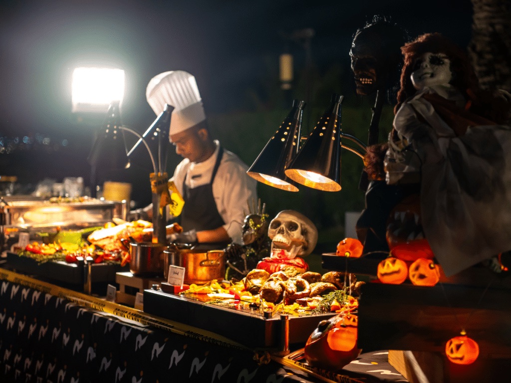 Chef at a live cooking station decorated with skulls and pumpkins at the London Social Wicked Brunch, Ritz-Carlton Dubai