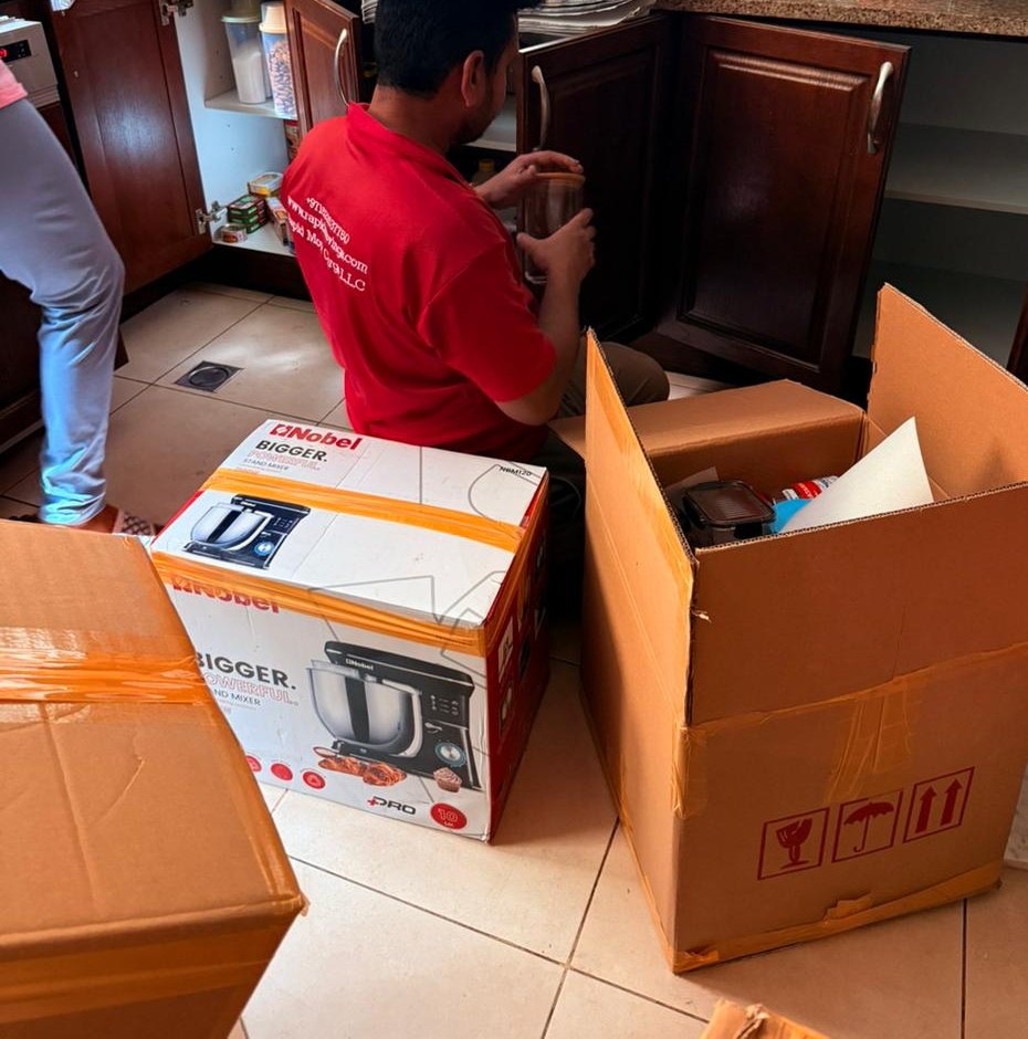 Dedicated packer clearing kitchen cupboards during a Dubai villa move