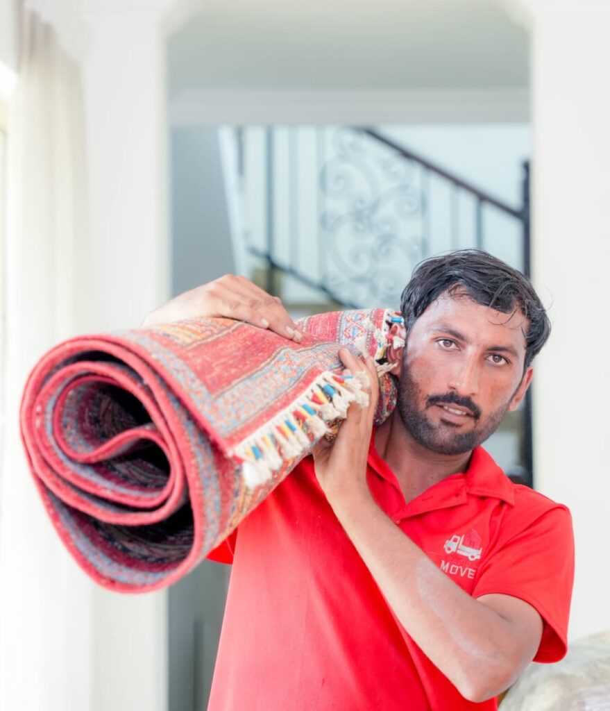 Mover carrying a rolled rug out of a Dubai villa