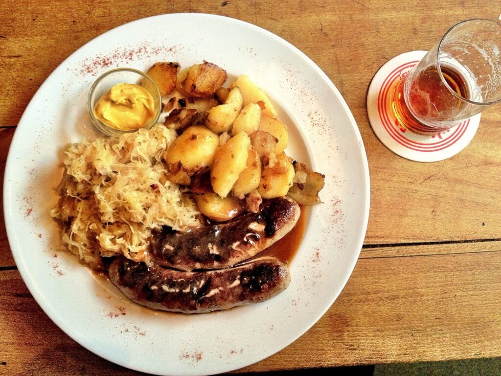 German bratwurst with sauerkraut, roast potatoes, mustard and a glass of beer
