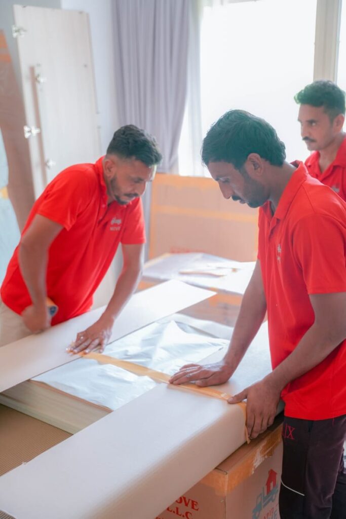 Packers building a cardboard crate around furniture during a Dubai villa move