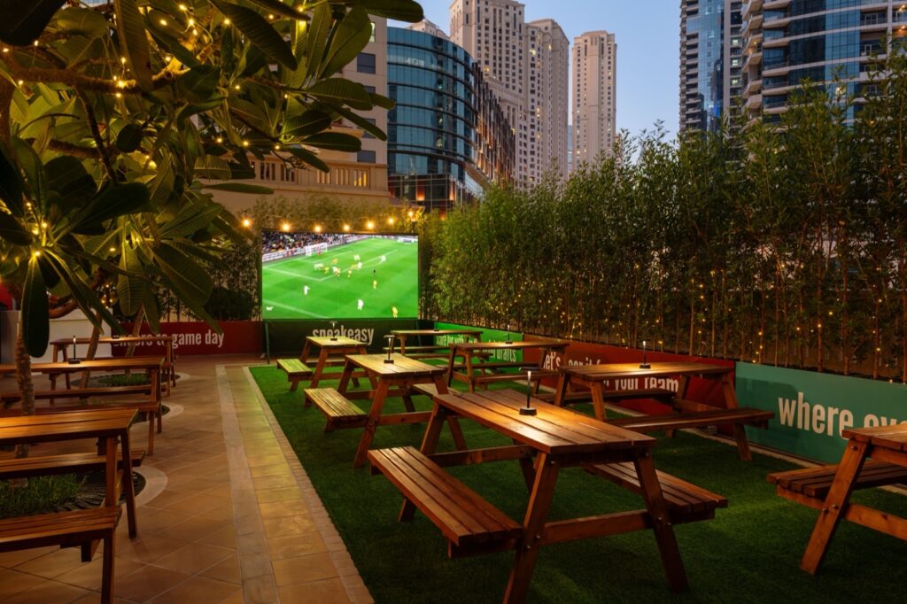 Outdoor garden with picnic benches and a big screen at Speakeasy, Sheraton The Walk JBR