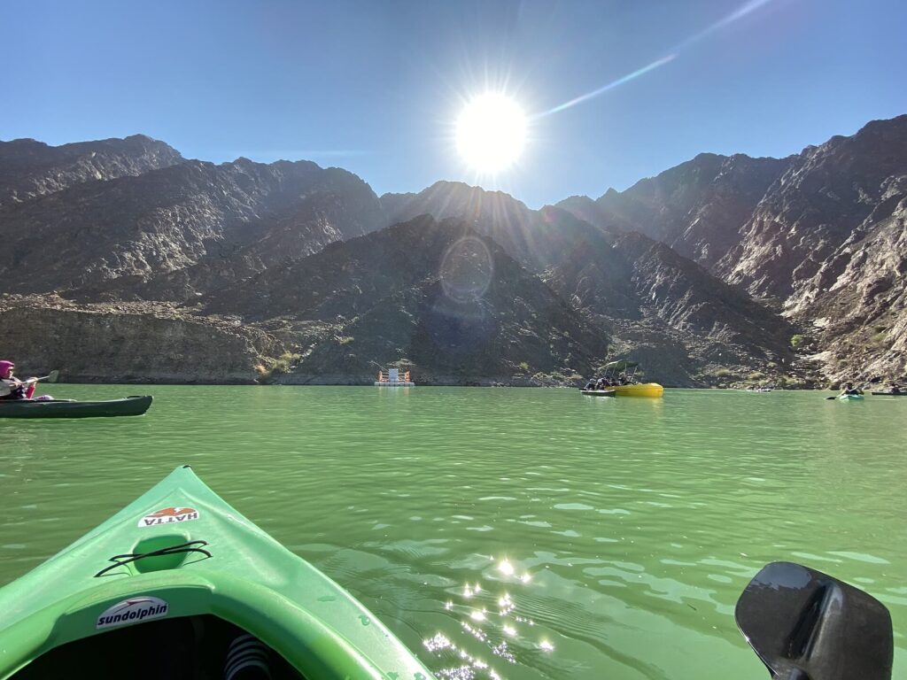 Kayak on the green water of Hatta Dam with the Hajar Mountains behind