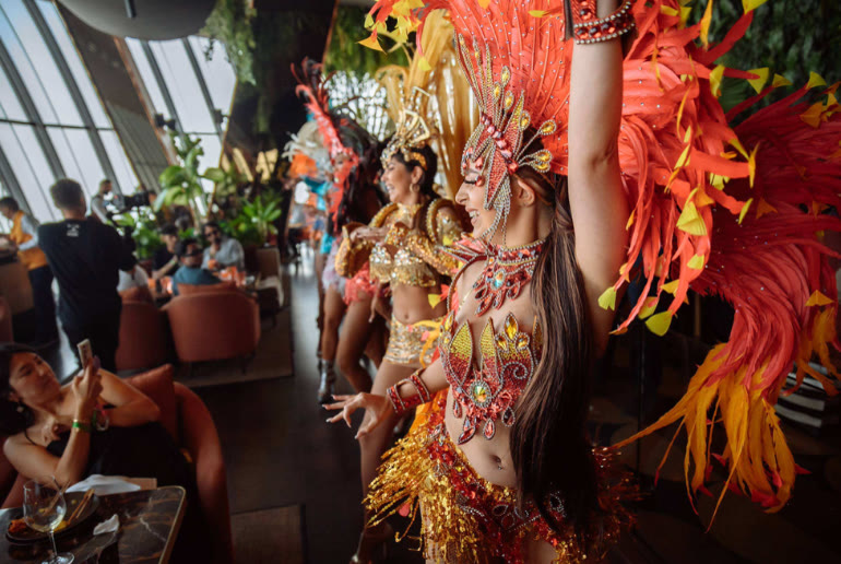 Samba dancers in feathered costumes performing at the SUSHISAMBA Dubai Rio Brunch